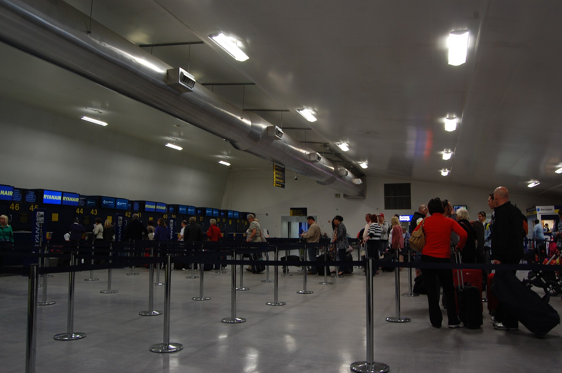 Travellers and check-in desks in an airport departure hall.